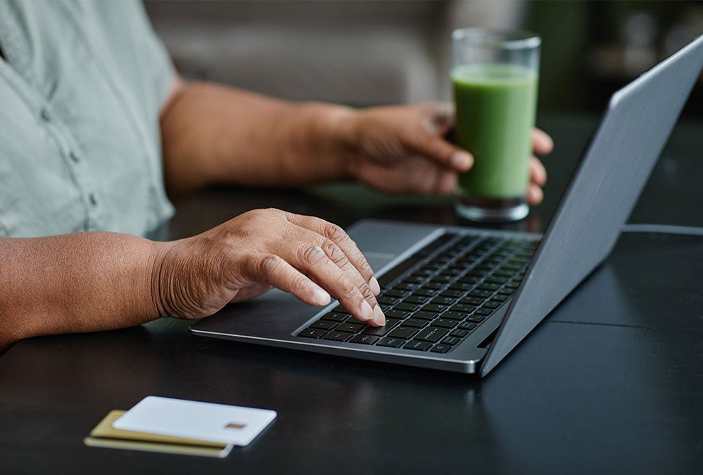 woman using laptop drinking smoothie