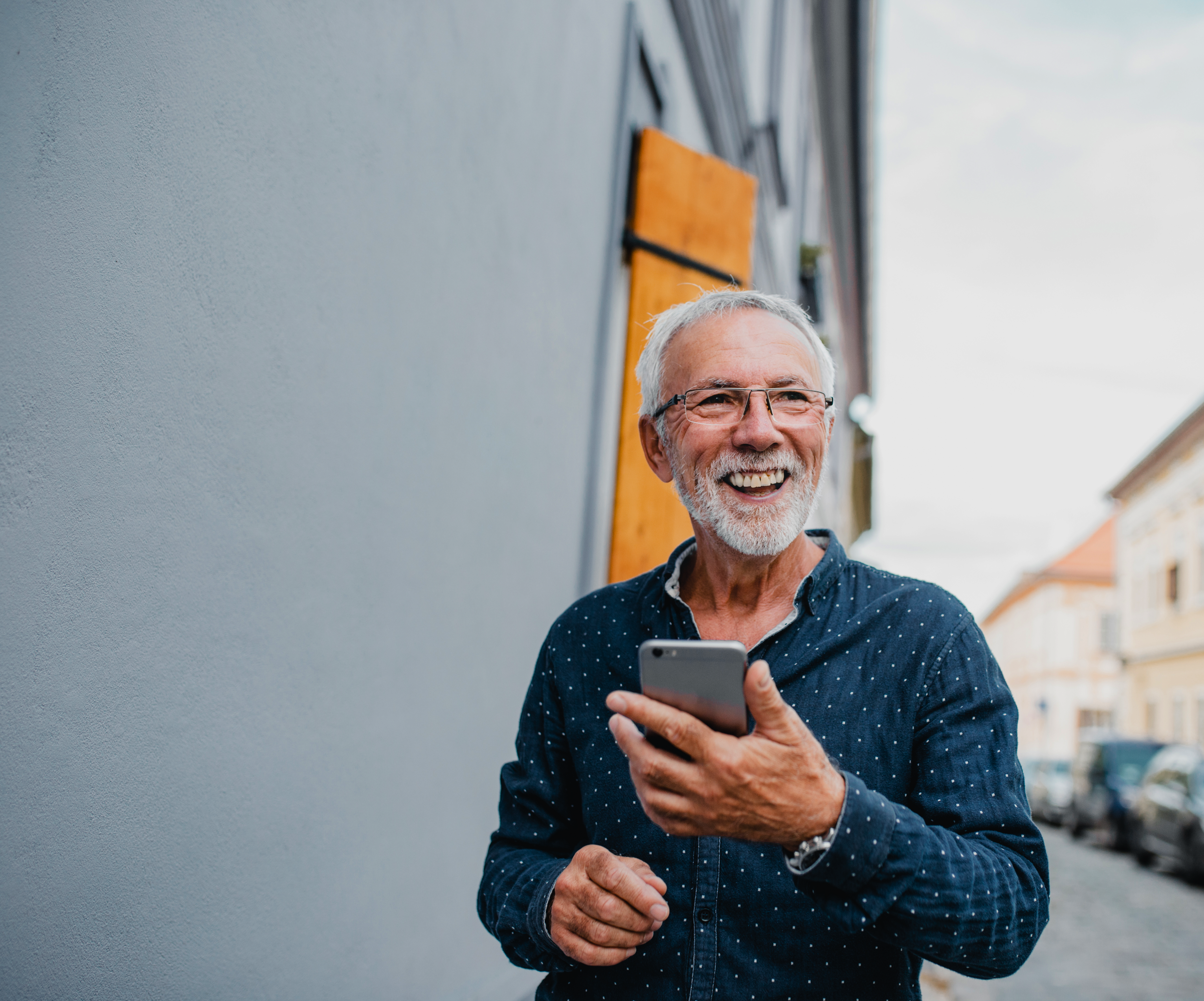 smiling senior man using phone on street