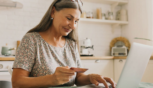 woman using a laptop holding a card