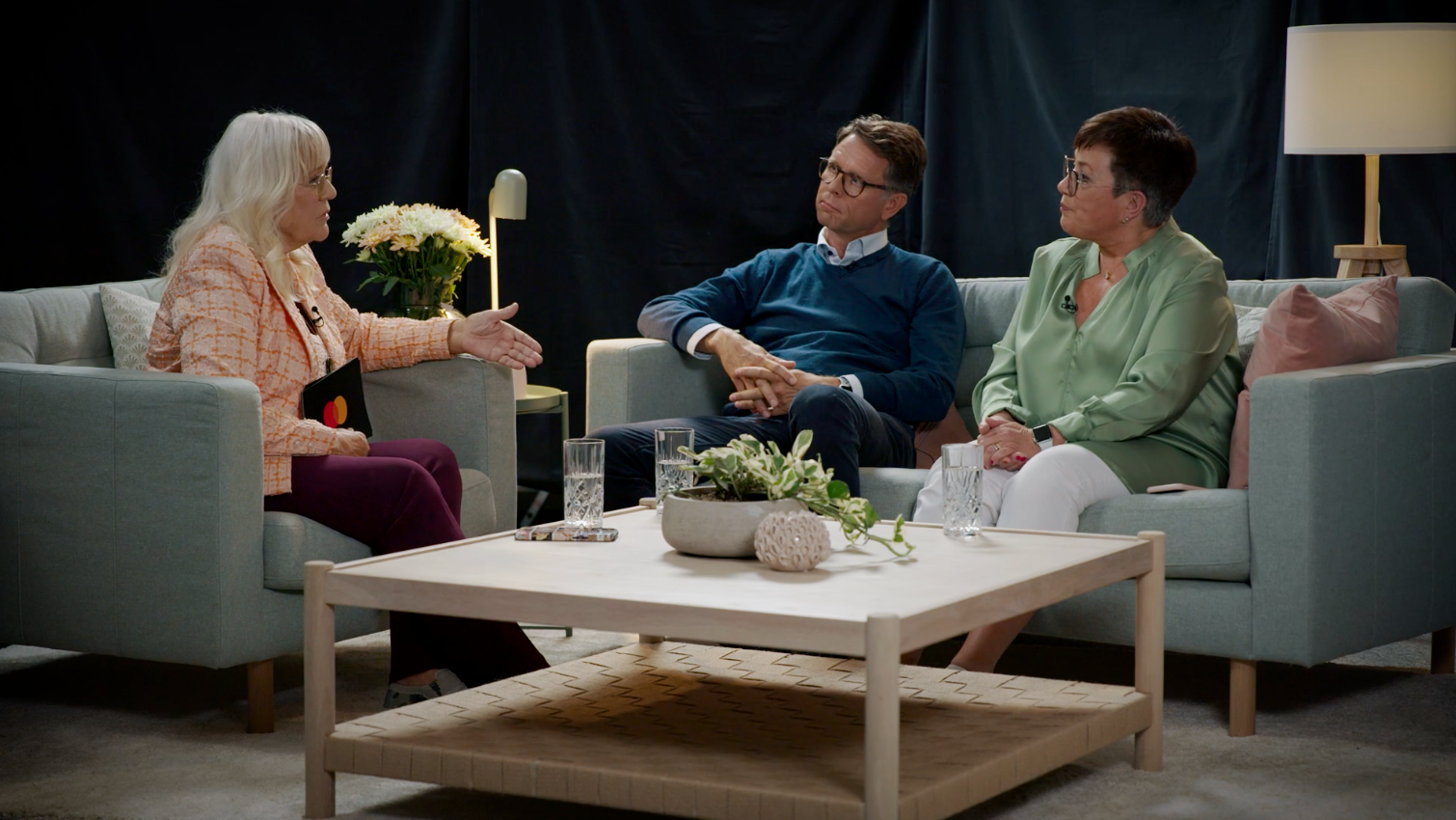 two women and a man sitting on couches