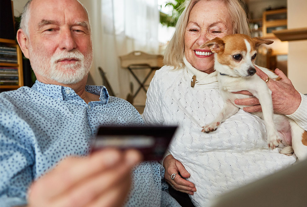Older couple wit a small dog looking at a payment card