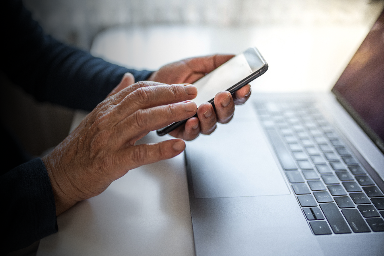 Senior person using mobile phone and laptop at home