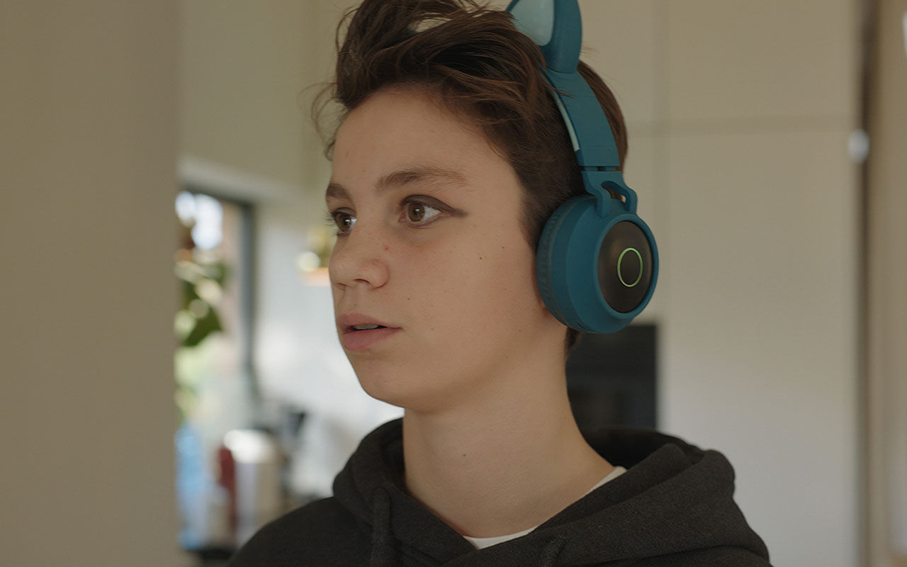 En person bär hörlurar och står inomhus.