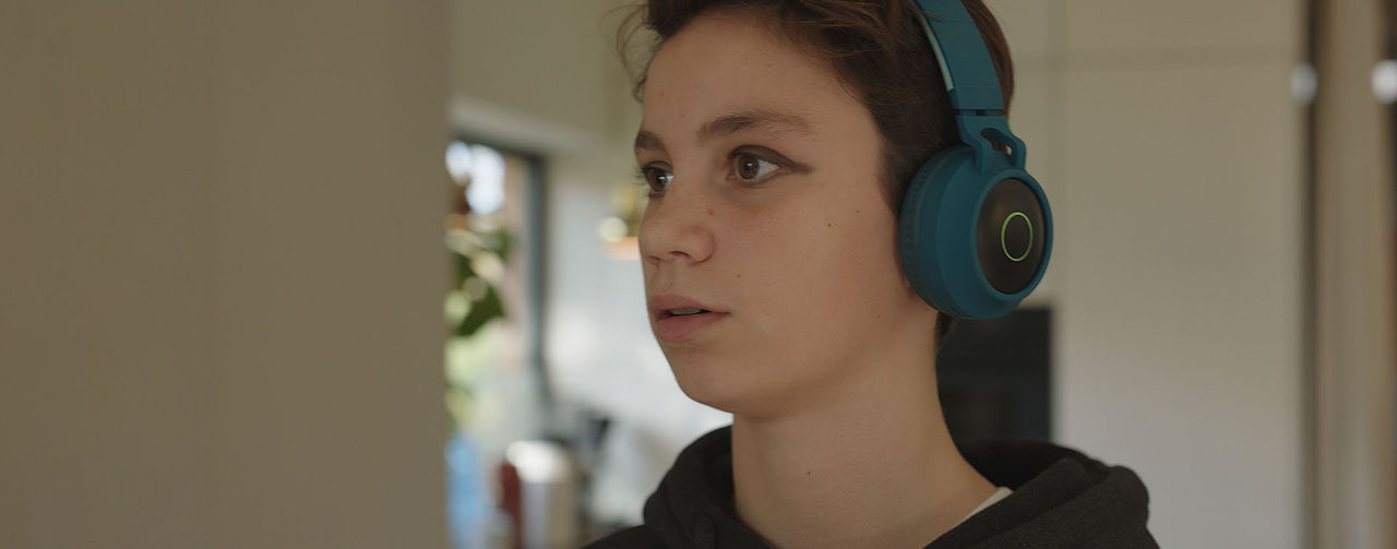 En person bär hörlurar och står inomhus.